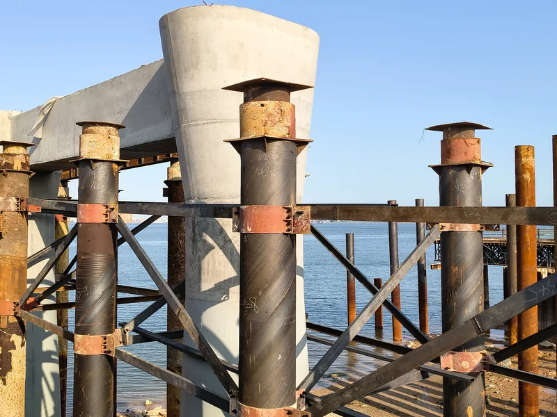 Pile-head jacks and capping plates under a pier cap