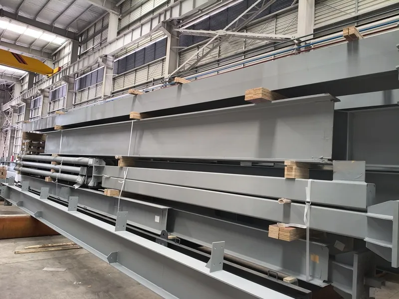 Long welded girders and railing sections stored inside the workshop