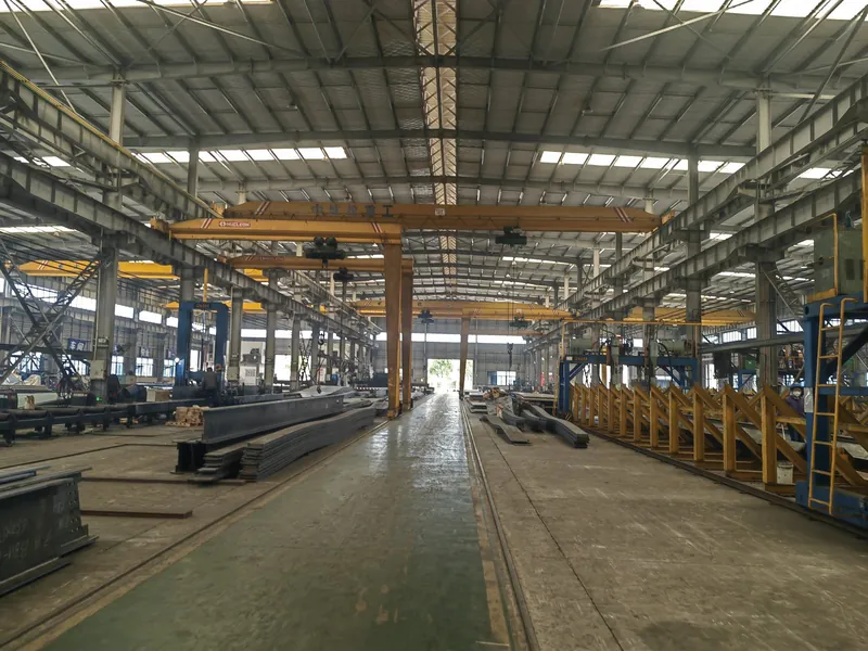 Steel fabrication hall with overhead gantry cranes, plate storage and a marked production bay