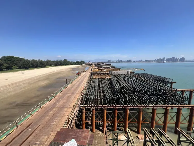 Bailey truss deck and steel trestle under construction over tidal water